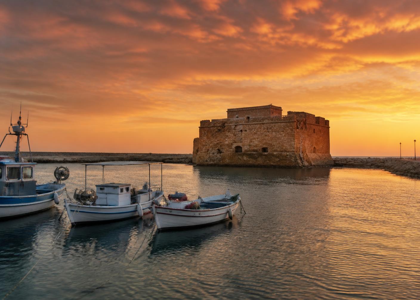 Paphos harbour and castle at sunset with traditional fishing boats